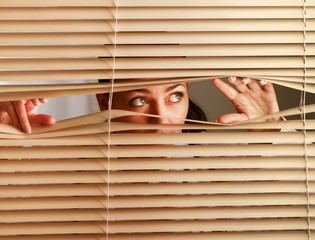 Portrait of a woman looking through out the blinds