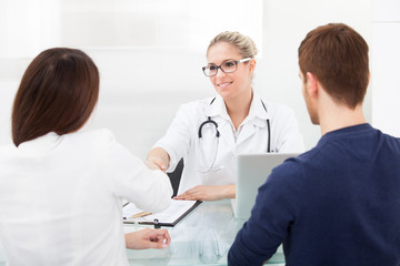 Fototapeta na wymiar Doctor Shaking Hands With Couple