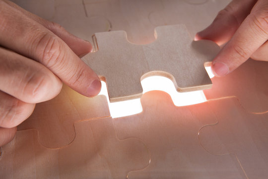 Businessman Fixing Jigsaw Pieces At Desk