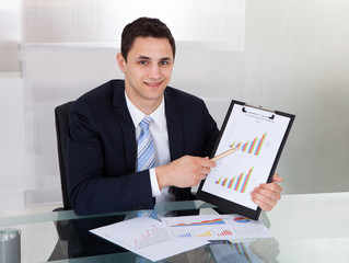 Confident Businessman Showing Graphs In Office