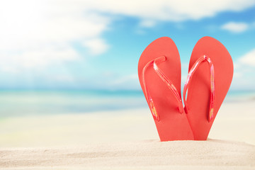 Summer beach with red sandals in sand