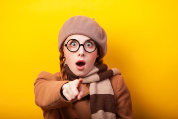 Redhead girl in coat and scarf on yellow background.