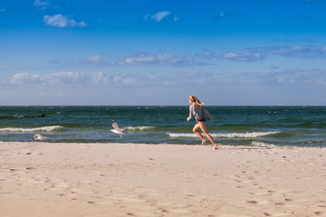 Mädchen jagt Möwen am Strand