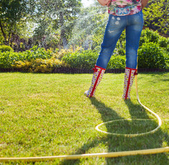 Woman holding garden water hose watering garden
