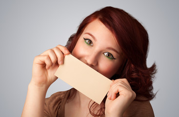 Cute girl holding white card at front of her lips with copy spac