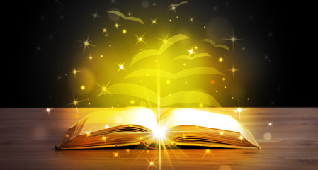 Open book with golden glow flying paper pages