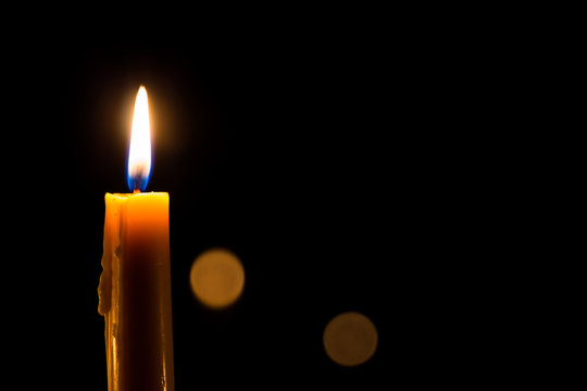 Yellow candle on the dark background with bokeh