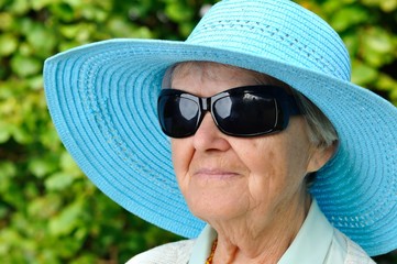 Senior woman in blue hat in garden.