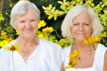 Senior and mature women in garden full of flowers.