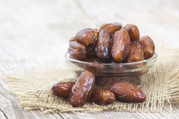 dried dates in a bowl on wooden background