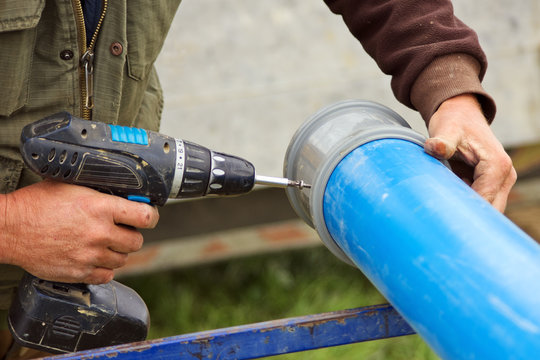 Worker drilling holes on plastic water pipe