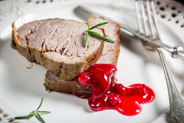 Venison served with cranberry sauce on white plate