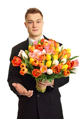 Young man at suit you offers big bouquet of tulips