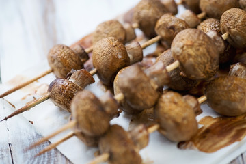 Close-up of baked champignons on skewers, studio shot