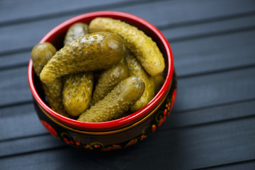 Pickled cucumbers in a khokhloma bowl, black wooden background