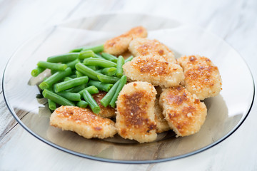 Glass plate with chicken nuggets and boiled beans, studio shot