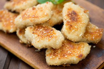 Close-up of sesame chicken nuggets on a wooden chopping board