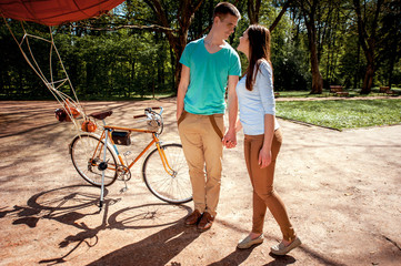 Young and joyful couple having fun in the park with bicycle and