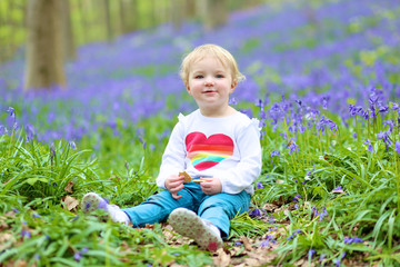 Happy little girl relaxing in bluebells forest