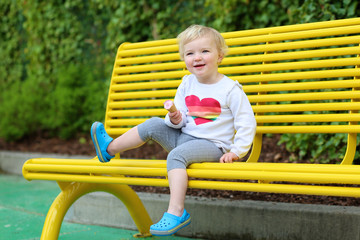 Fototapeta na wymiar Happy little girl enjoying ice cream outdoors in the park