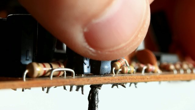 Hand pulling out condenser from board