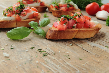 Bruschetta with fresh tomato and herbs on wooden table