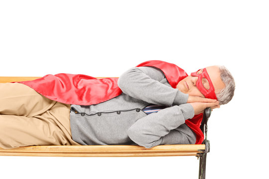 Senior Man In Superhero Costume Sleeping On Bench