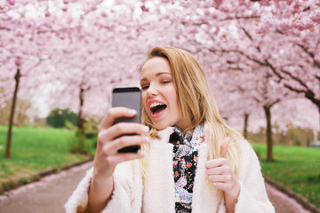 Cheerful young woman photographing herself at spring park