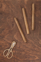 three cigars and gold scissors on the old table