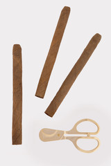 three cigars and gold scissors on a white background