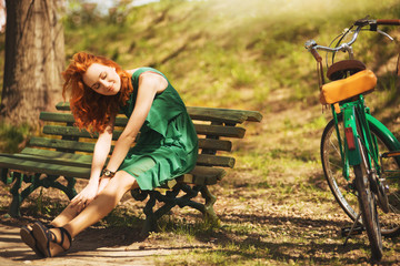 Red-hair woman is seating with retro bicycle