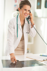 Happy medical doctor woman with fluorography talking phone