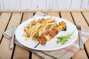 plate of French fries with a skewer of meat