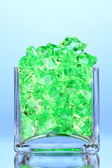 A glass with green decorative stones on blue background