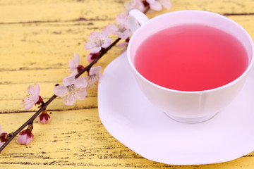 Fragrant tea with flowering branches on wooden table close-up