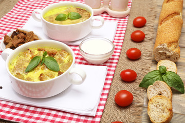 Tasty soup in saucepans on wooden table, close up