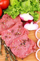 Raw beef meat with vegetables on table close up