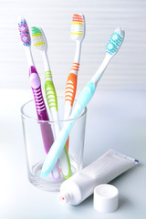 Toothbrushes in glass on table on light background