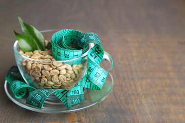 Raw green coffee beans in glass cup and measuring tape,