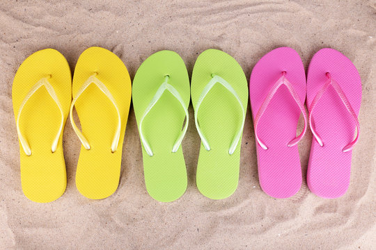 Bright flip-flops on sand, close up