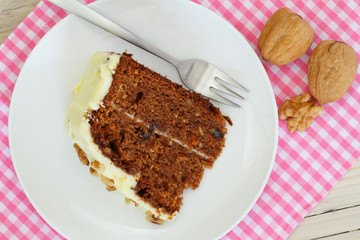 Carrot cake with walnuts and marzipan icing on pink napkin