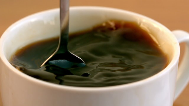 Teaspoon stirring coffee in a cup