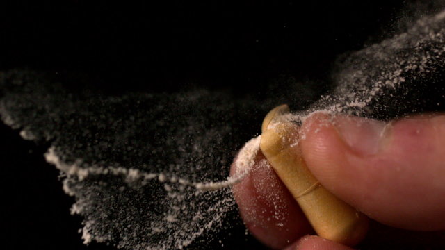 Fingers squeezing and breaking a pill capsule