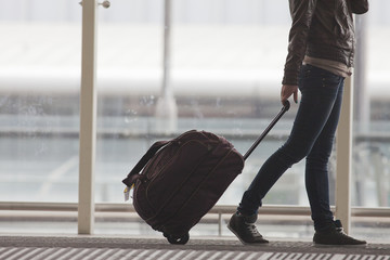 Frau trägt Ihr Gepäck am Flughafenterminal