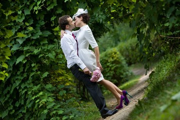 Naklejka na ściany i meble Wedding theme. The groom kisses the bride in a botanical garden.