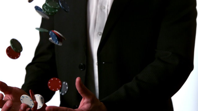 Man in suit catching falling casino chips