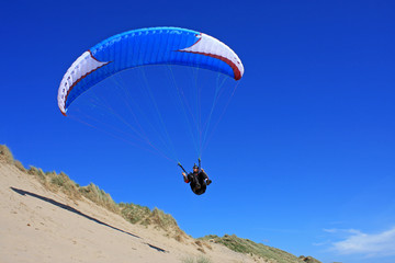 paraglider over sand dunes