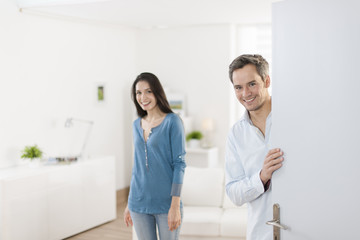 Obraz premium Cheerful couple inviting people to enter in home