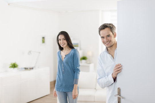 Cheerful couple inviting people to enter in home