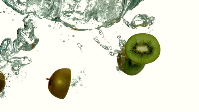 Kiwi pieces plunging into water on white background